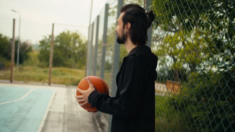 Basketball-coach-in-a-black-jacket-replaces-a-basketball-to-a-basketball-player.-Black-person.-Playing-basketball-with-a-coach-is-the-way-to-success