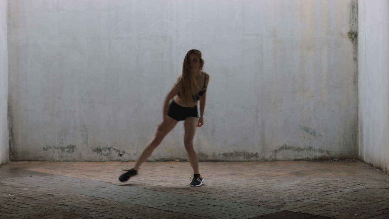 mujer bailarina hermosa joven bailarina de calle caucásica realizando movimientos contemporáneos disfrutando de la expresión de la danza moderna practicando en un almacén grungy