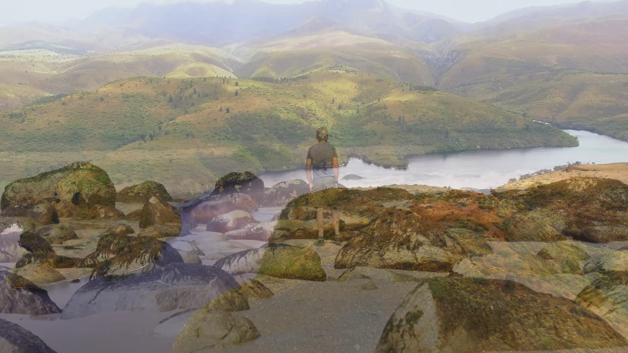 male hiker exploring shoreline by lake and hills, displaying animated education map overlay