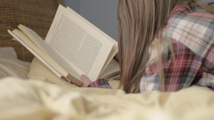 Donna a letto che legge un libro.