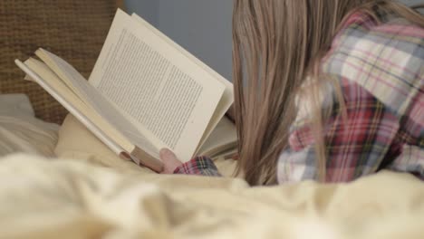 mujer en la cama leyendo un libro mediano.