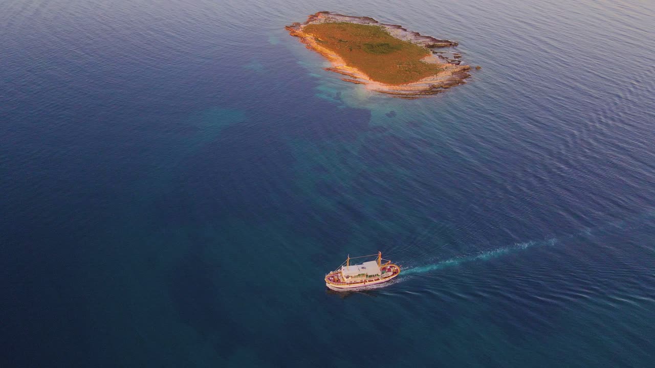 밝은 파란 바다 한가운데에 있는 그림 같은 섬의 멋진 드론  ⁇ 은 여행을 시작할 준비가 된 보트도 보여줍니다.