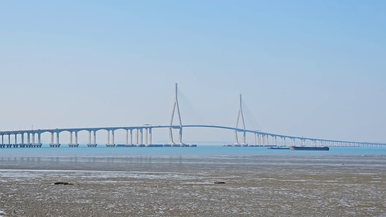 The Incheon Bridge stretches elegantly over blue waters, with fishery boats and massive freight container ships navigating below, connecting Incheon Airport to Songdo's bustling smart city