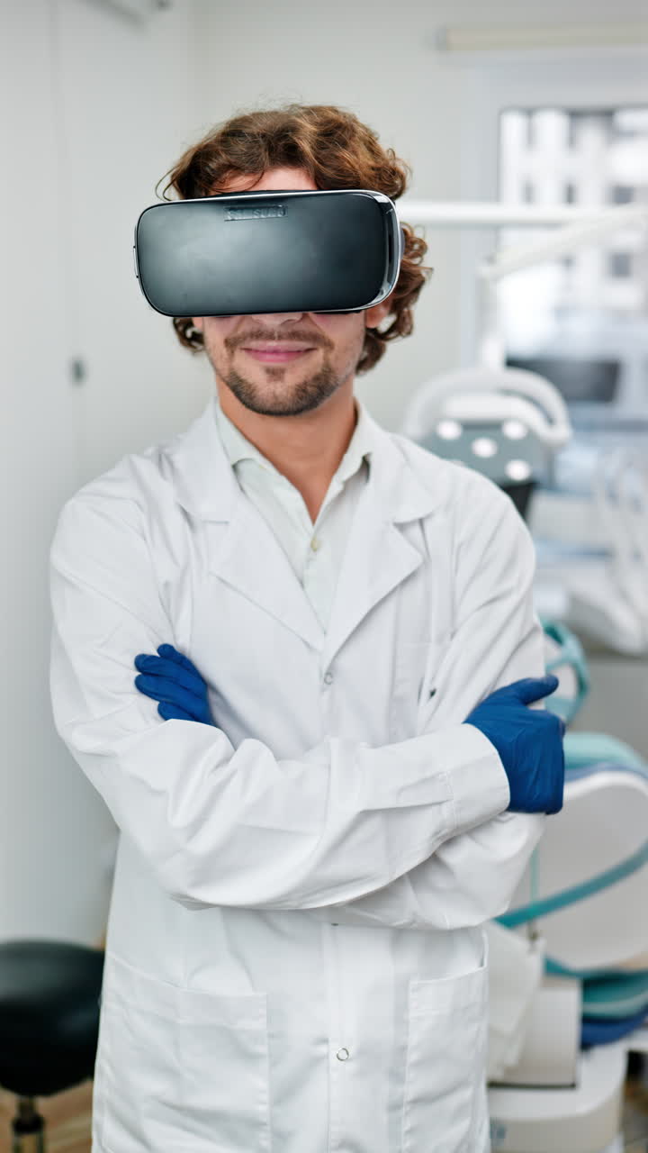 Dentist wearing a scrub and a Virtual Reality headset while standing and smiling in a dental cabinet. Vertical