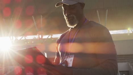 smiling african american male coach making notes on sunny day