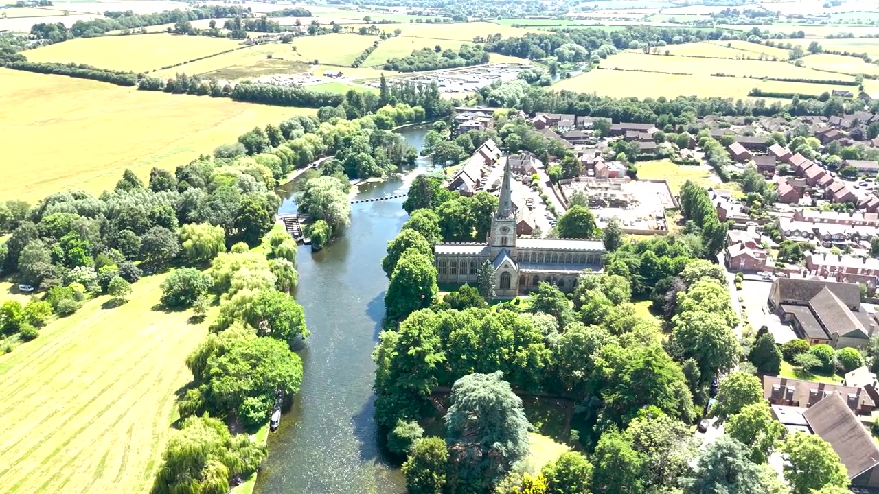 Un dron captura una amplia vista aérea de la Iglesia de la Santísima Trinidad a orillas del río Avon en Stratford-upon-Avon, Inglaterra, la iglesia parroquial donde está enterrado William Shakespeare