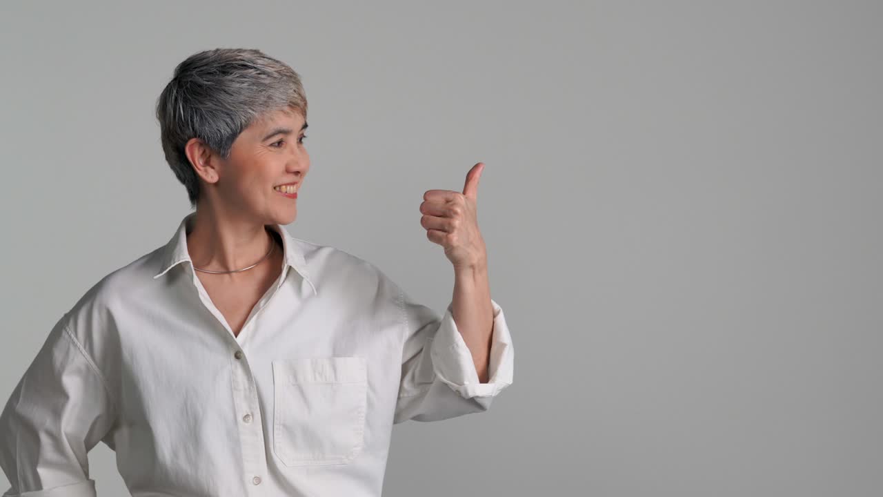Asian woman pointing fingers up at empty copy space
