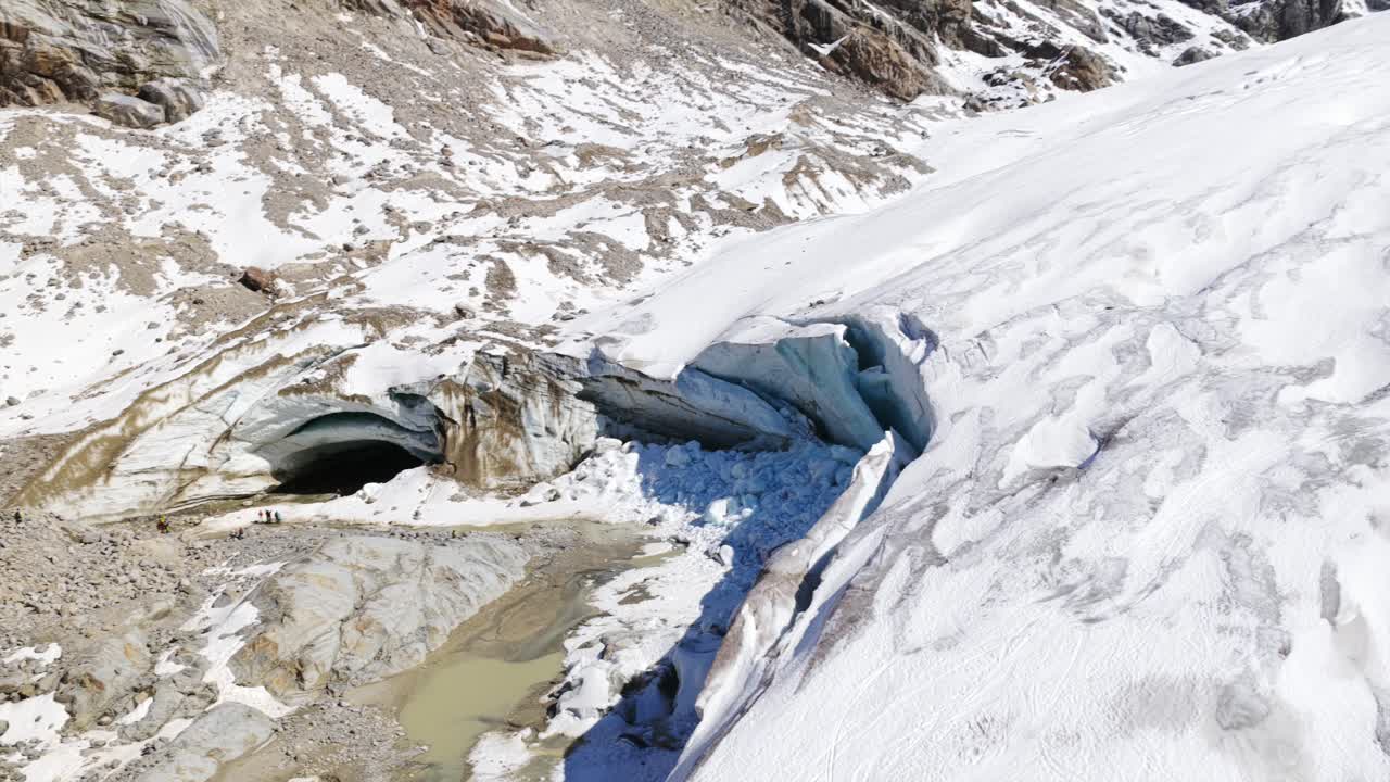 Ice cave entrance on Morteratsch Glacier, with crevasses and meltwater channels, climate change, Switzerland. Aerial drone pov