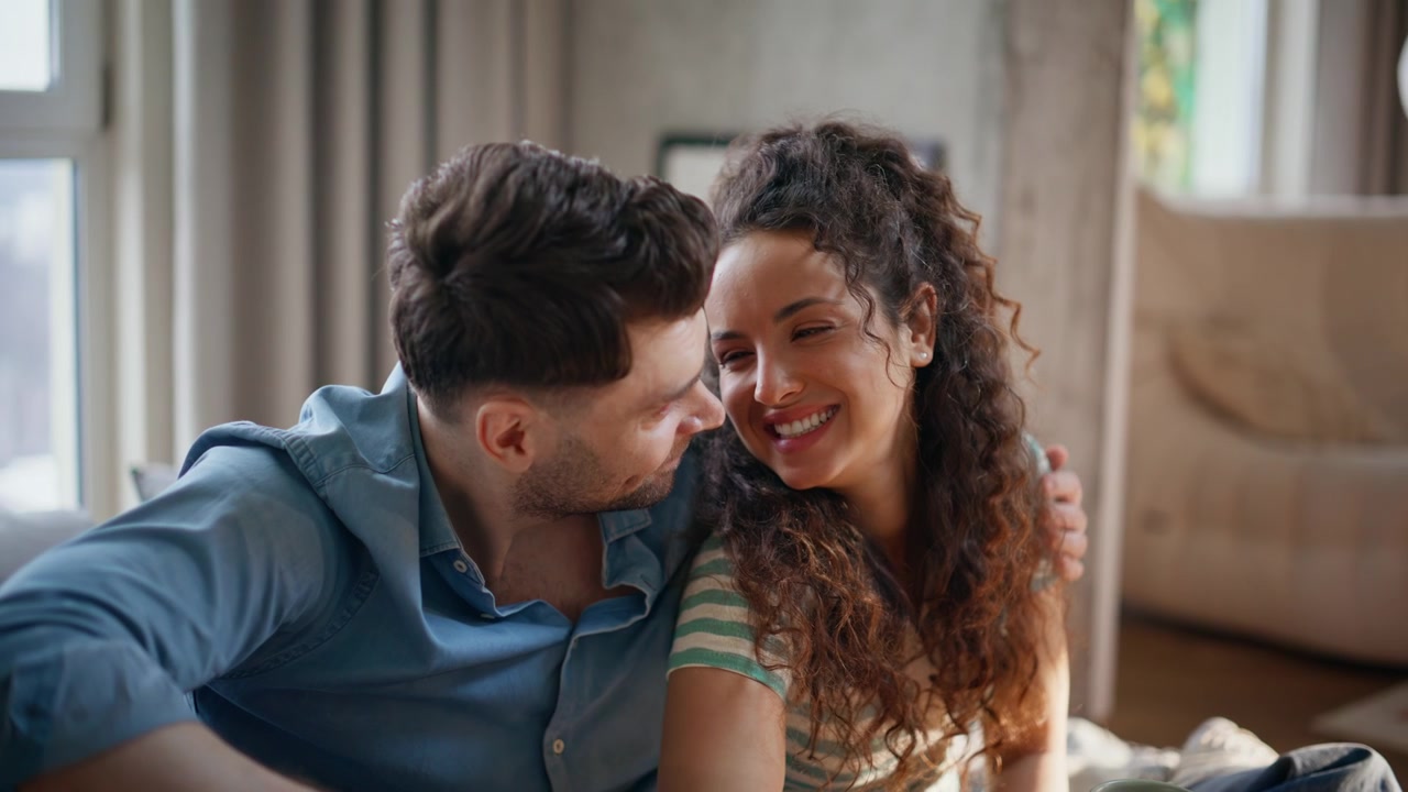 Tender couple embracing drinking coffee home. Close up young pair cozy morning.