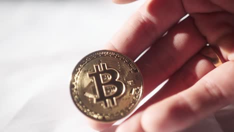 Person's-Hand-Holding-A-Gold-And-Shiny-Bitcoin-Coin