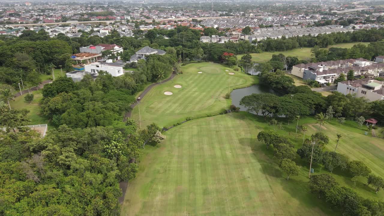 나무, 주택, 연못, 고속도로가 있는 골프 코스의 조감도