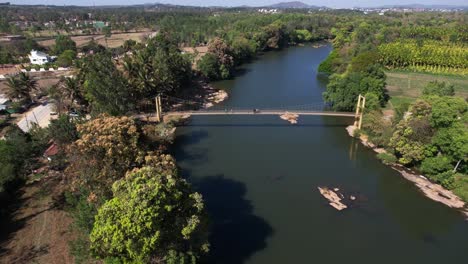 toma cinematográfica de un puente colgante de madera colgado sobre un famoso río en la india
