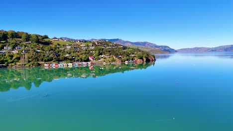 aerial footage captures akaroa harbour's serene waters and lush hills under clear blue skies, showcasing natural beauty and tranquility