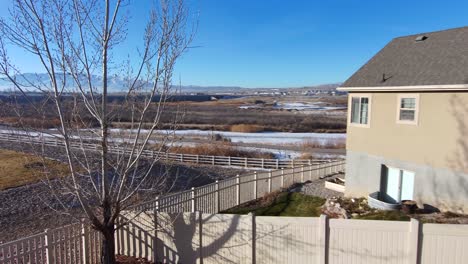 Aerial-view-of-the-snowy-mountains-and-countryside-then-turn-and-fly-to-see-a-senior-man-on-his-backyard-deck-drinking-a-coffee-in-the-morning-sunshine