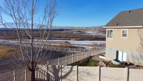 vista aérea de las montañas nevadas y el campo, luego gire y vuele para ver a un anciano en la terraza de su patio trasero tomando un café bajo el sol de la mañana
