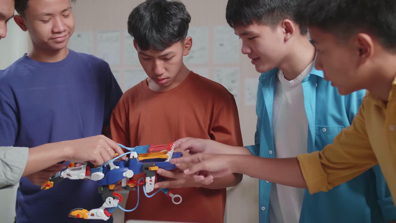 grupo de jóvenes chicos asiáticos con impresión 3d comparando una mano cyborg con las imágenes en una computadora portátil mientras trabajan en casa