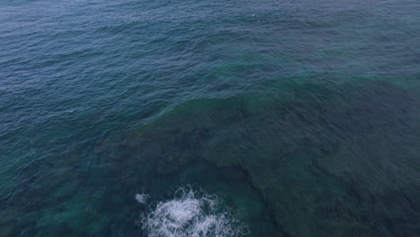 Pull-back-over-the-Pacific-Ocean-and-up-over-the-shore-at-Sandy-Beach-Park-in-Oahu,-Hawaii-on-at-sunset