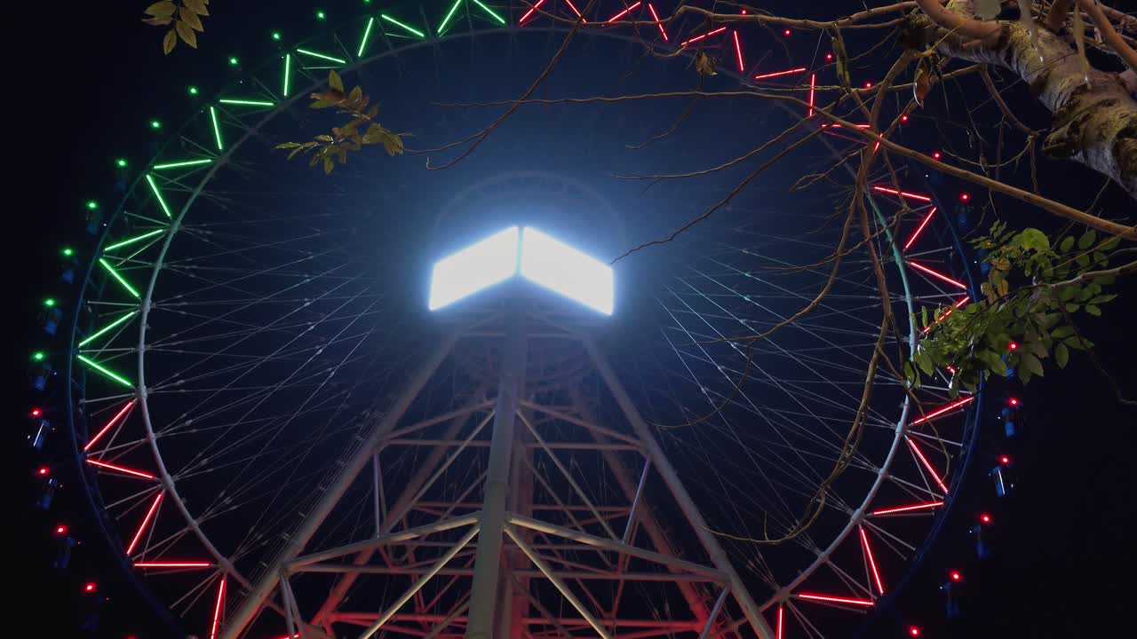 lapso de tiempo de una rueda grande dando vueltas iluminada con luces cambiantes de colores en la noche