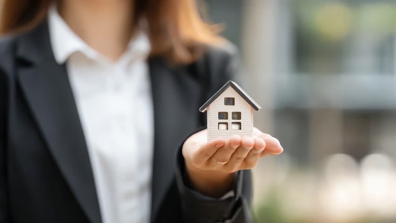 Un individuo seguro de sí mismo presentando una maqueta de casa en miniatura, enfatizando la pasión y profesionalidad por el sector inmobiliario en un entorno de negocios.