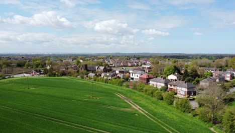 Aerial-view-rural-Cheshire-countryside-farming-village-surrounded-by-farmland-meadow-fields,-England