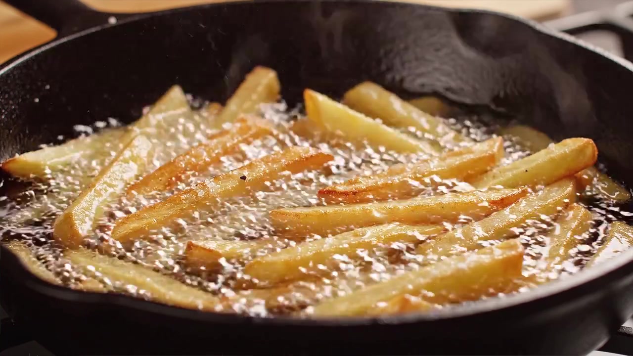 Gyldne pommes frites frituresteges i en støbejernspande