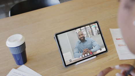 mujer de negocios caucásica en una videollamada con un colega afroamericano en la pantalla