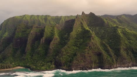 hermosa vista de la naturaleza, drones volando sobre los picos de las montañas de la selva verde que revelan una playa tropical en el parque napali 4k