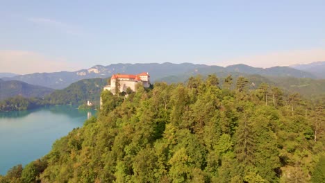 smooth cinematic dolly in aerial to reveal bled castle overlooking lake bled high in the julian alps in slovenia