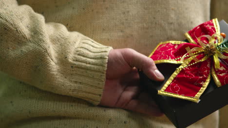 close up of young man holding present behind his back