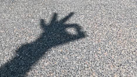 sequence of shadow hand signs on pavement.