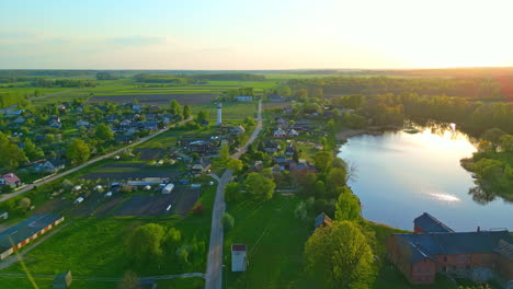 Volando-Sobre-Un-Municipio-Rural-Construido-Junto-A-Un-Pequeño-Lago-Rodeado-De-Campos-Verdes