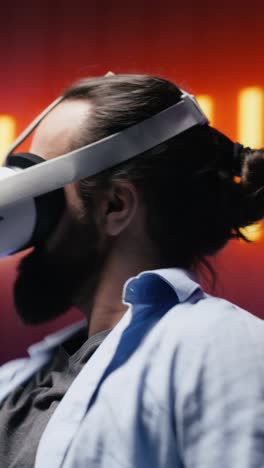 vertical video artsy young guy immersed in virtual reality under neon lights and cyberpunk glow