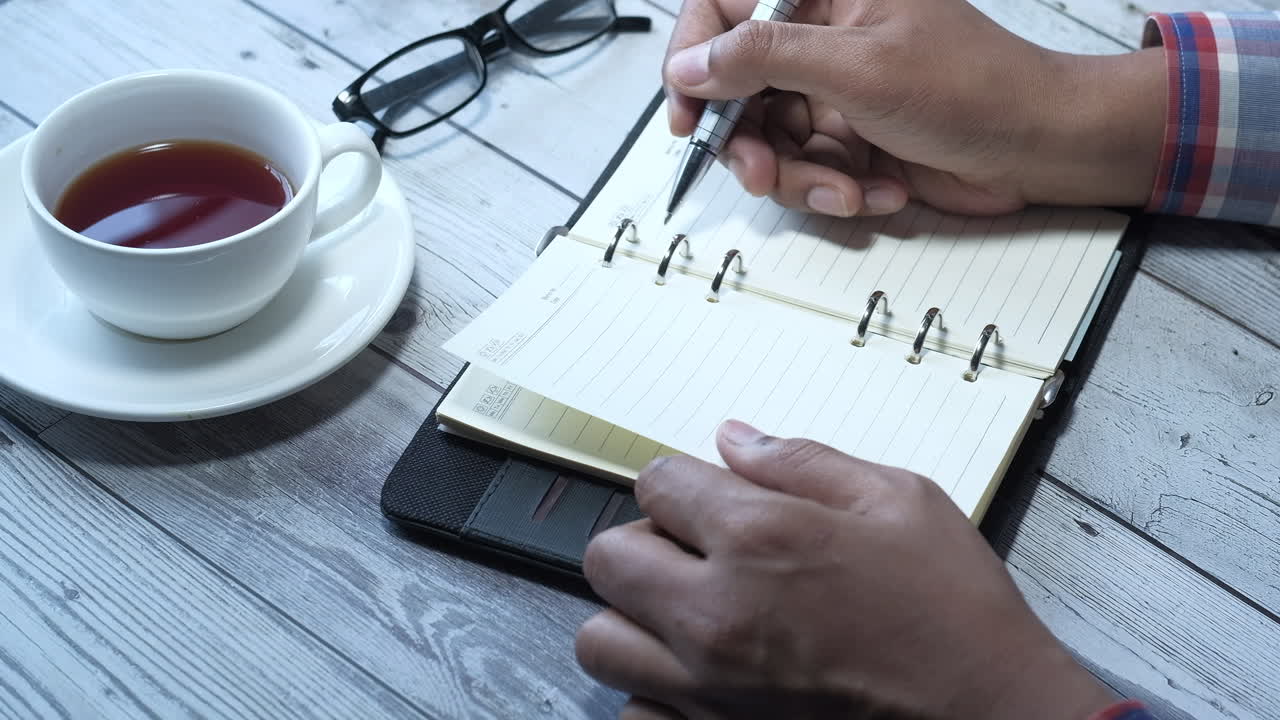 차 한 잔 과 안경 을 가지고 노트북 에 쓰고 있는 사람