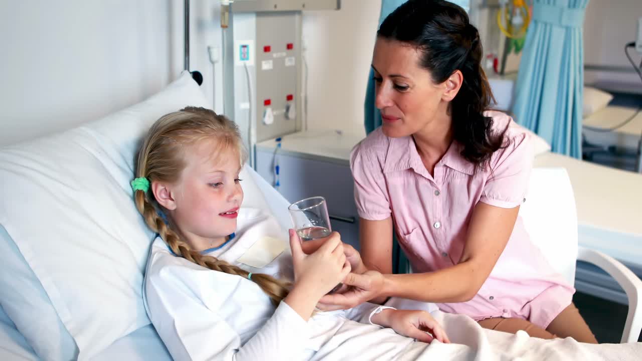 Mother giving medicine to her sick daughter