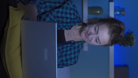 video vertical de una mujer feliz usando una computadora portátil por la noche.
