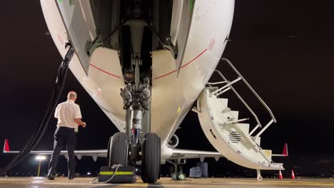 piloto haciendo el recorrido externo a un jet moderno durante una escala en la noche