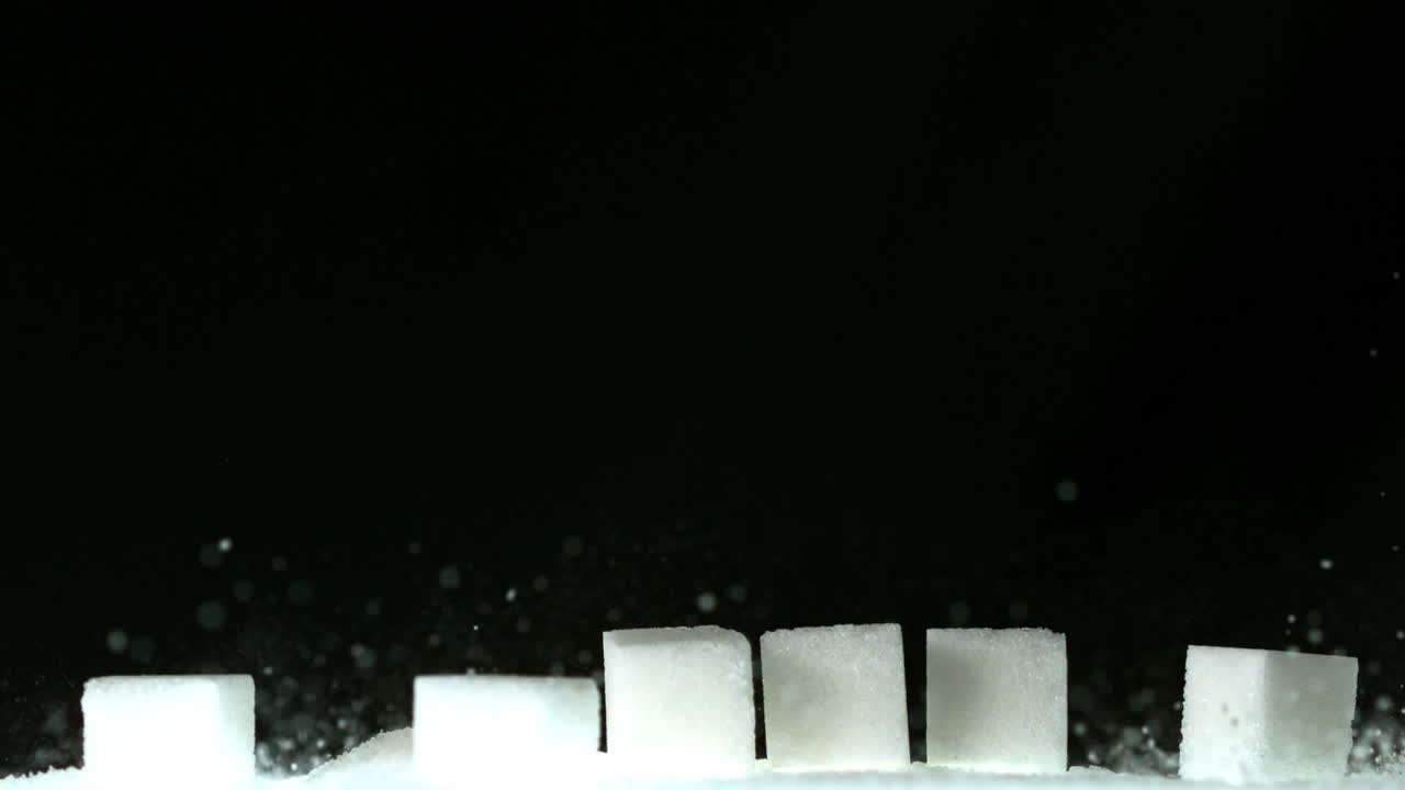 cubos de azúcar cayendo sobre una pila de azúcar