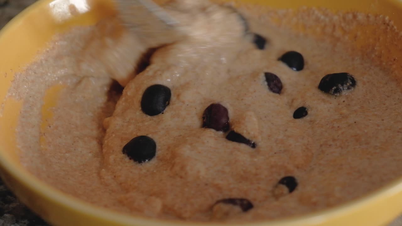 그릇에 담긴 달콤한 반죽 위에 블루베리를 던지고 포크와 섞는 여자