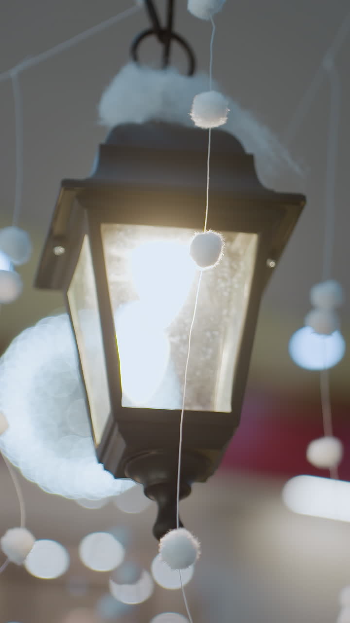 Elegant decorative lantern glowing warmly in a beautifully adorned mall, surrounded by festive white hanging ornaments and blurred holiday lights