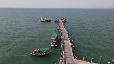 steady aerial footage of the pattaya fishing dock with three fishing boats docked while the waves move them in pattaya, thailand