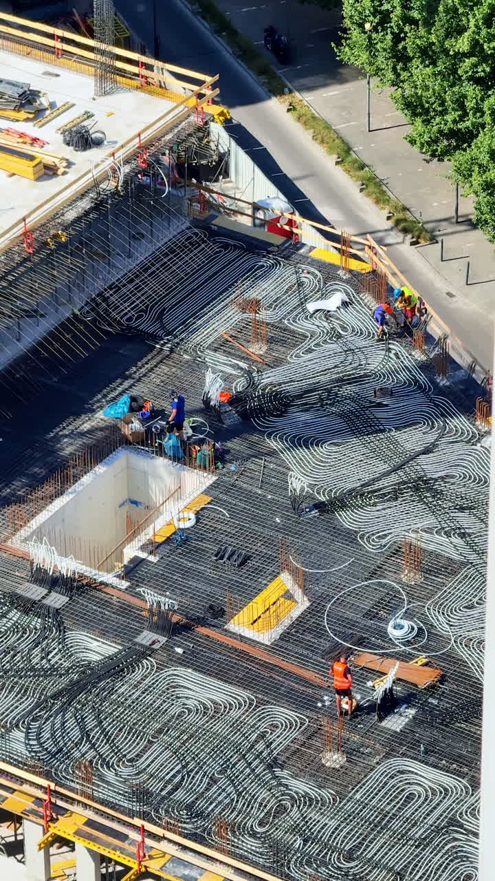 Urban construction with workers. Numerous workers are active on a construction site, laying out materials in an urban setting during daylight hours