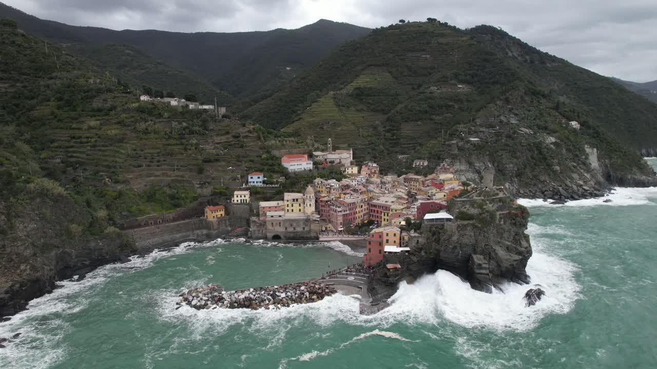 drone orbital aéreo disparado de izquierda a derecha de cinque terre pueblo italiano ciudad junto a la playa olas chocando ángulo alto
