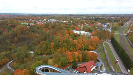 Vista-Aérea-Del-Paisaje-Otoñal-De-La-Sigulda-De-Bobsleigh-Y-Skeleton-Track-Luge-Track-Rodeada-De-Coloridos-Bosques-Durante-La-Temporada-Dorada-De-Otoño-En-Letonia