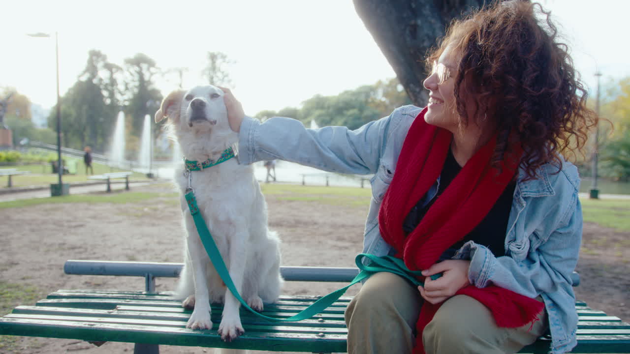 Female Owner Petting and Kissing Dog on Park Bench