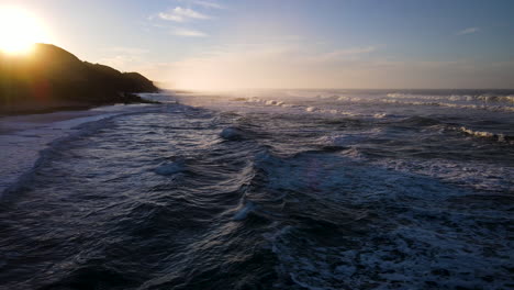 Flight-over-waves-at-Wilderness-beach-revealing-first-light-of-sunrise,-Garden-Route