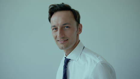 young dark-haired man fixes tie and smiles, close eye contact shot