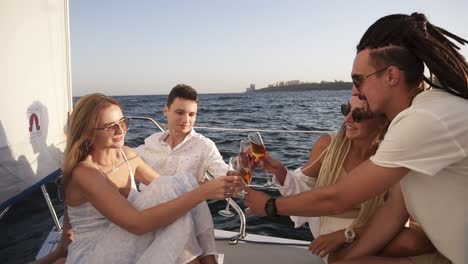 friends spend a weekend on a yacht. event on the yacht. merry company is celebrating a birthday on a yacht. group of four are clinking with the champange glasses and smilling