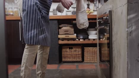 Lowsection-of-caucasian-man-opening-oven-in-kitchen,-slow-motion