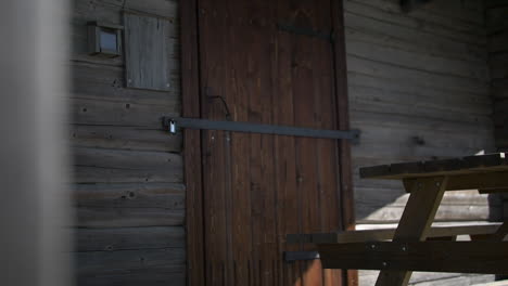 Puerta-De-Madera-Cerrada-Con-Llave-De-Un-Edificio-Rural,-Revela-La-Vista-De-Movimiento