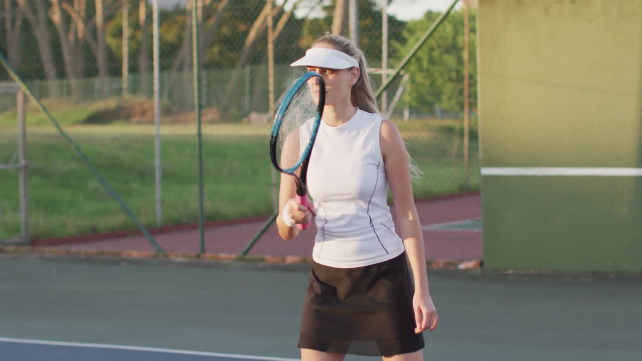 Playing tennis on outdoor court, woman wearing visor and athletic outfit